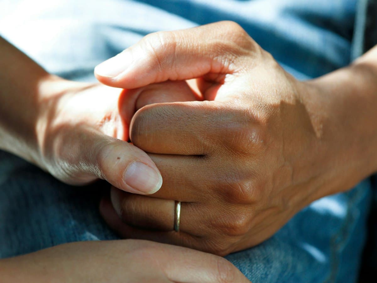 Two people holding hands in a gesture of support